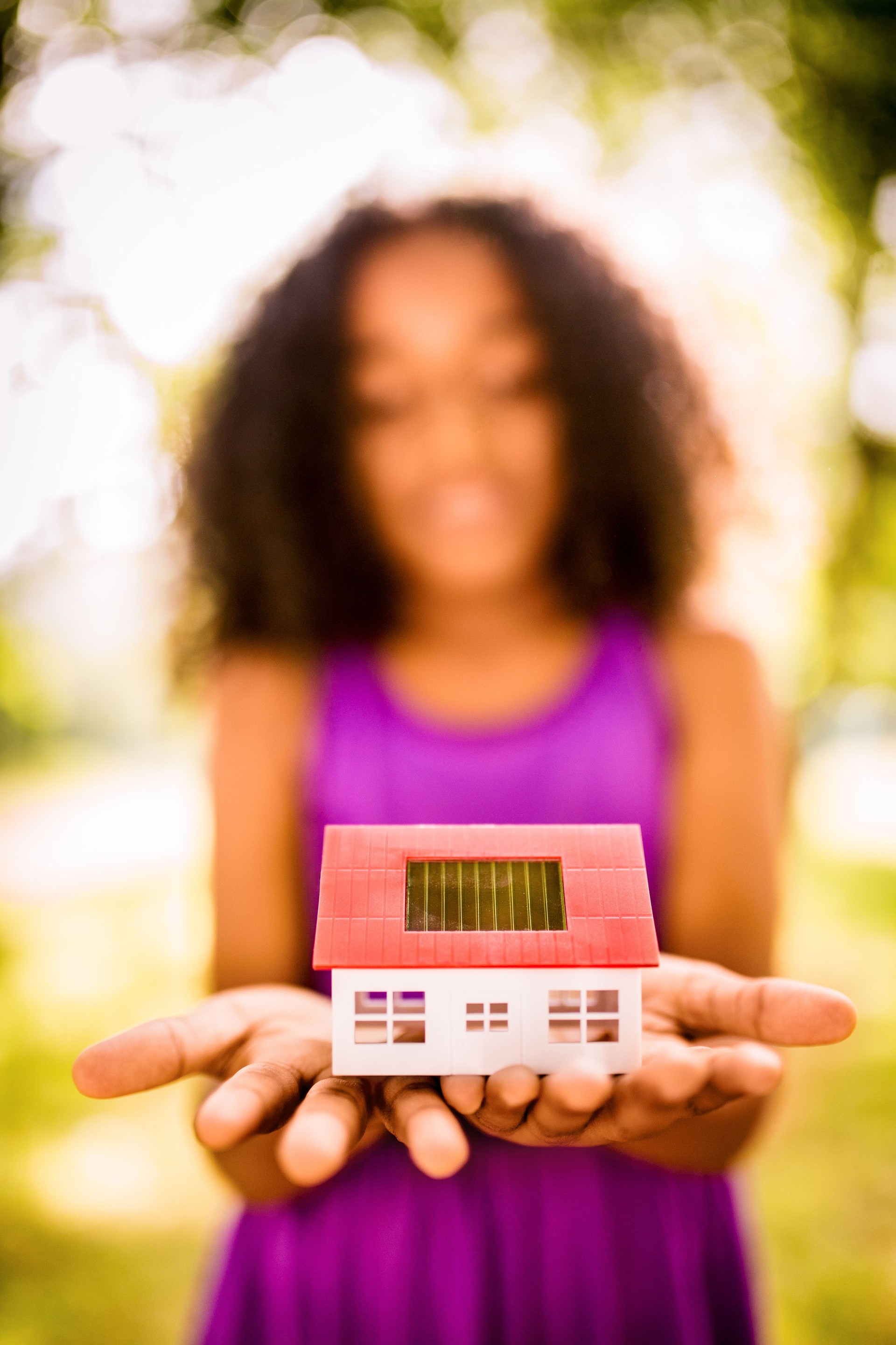 Casa giocattolo con celle solari trattenuta da ragazza Afro